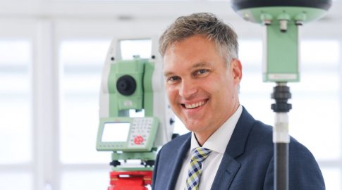 In einem Portrait lächelt Präsident Wolfgang Bauer zwischen Vermessungsgeräten in die Kamera.