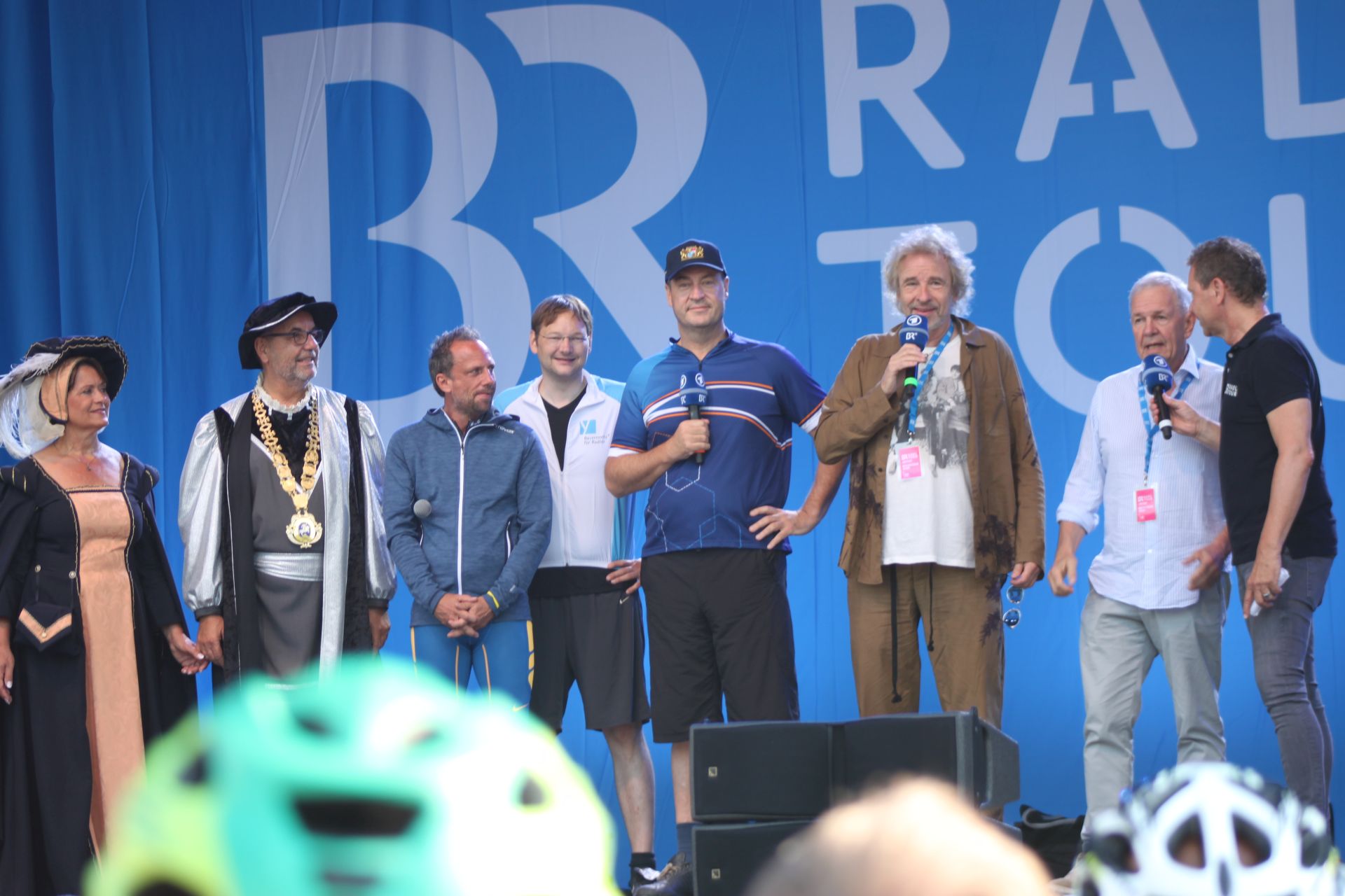 Acht Personen, darunter Thomas Gottschalk und Ministerpräsident Markus Söder stehen auf der BR-Radltour-Bühne und reden.